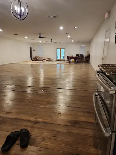Wet hardwood floor across a large open room before water damage drying starts